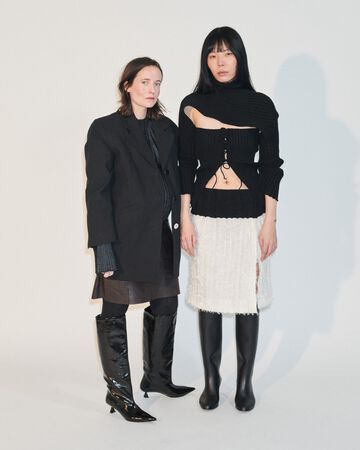 A. Roege Hove design looks: Two people displaying sheer, finely ribbed layered black and cream knitwear tops and a midi skirt